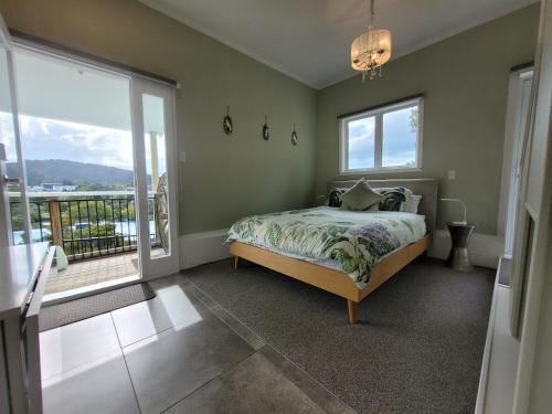 a bedroom with a bed and a balcony at Riverside Retreat in Whangarei