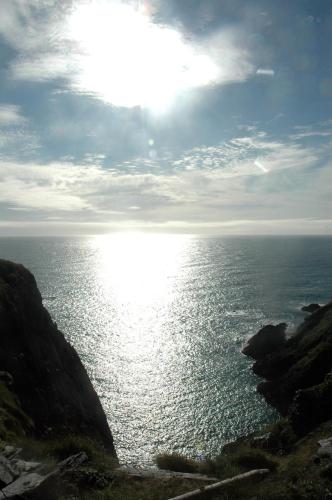 a body of water with the sun shining on it at Cosy Seaside Cottage Baltimore in Ballylinchy