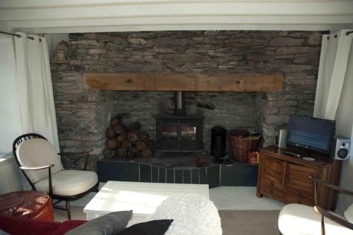 a living room with a stone fireplace and a tv at Cosy Seaside Cottage Baltimore in Ballylinchy