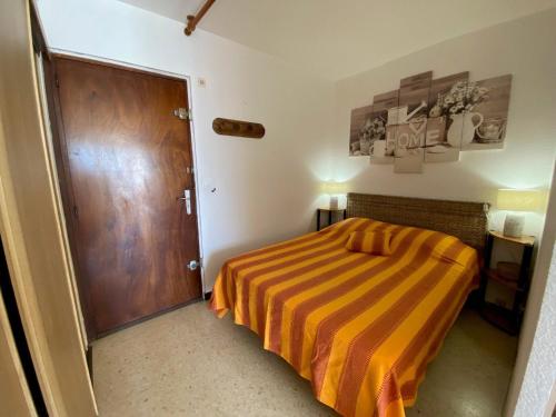 une petite chambre avec un lit et une porte en bois dans l'établissement Appartement 19m² avec Balcon, Proche Thermes et Etang de Thau - Parking Public - Animaux Admis - FR-1-503-46, à Balaruc-les-Bains