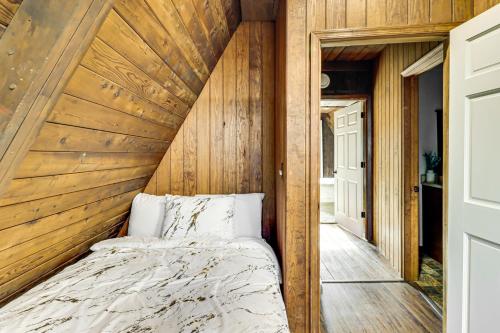 a bed in a room with a wooden wall at Hot Tub, Fire Pit and Patio A-Frame Stafford Cabin in Stafford