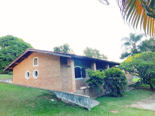 a brick house with round windows in a yard at Sítio Pand'Oro in Atibaia