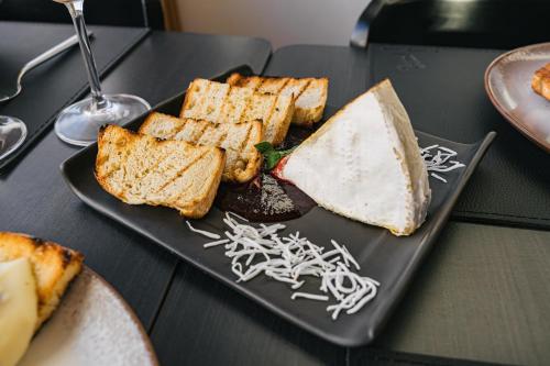a black plate with toast and bread on a table at Hotel Boutique Vinícola Araucária by Slaviero Hotéis in São José dos Pinhais