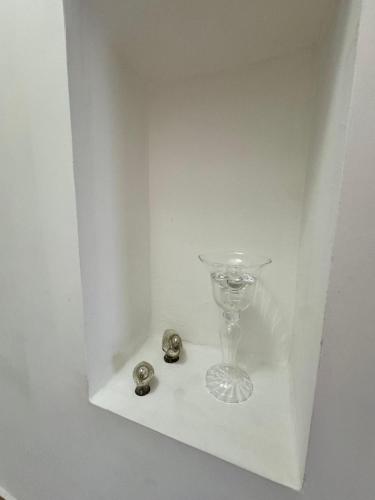 a white shelf with a glass vase and two buttons at Mare Apartment 4 in Scalea