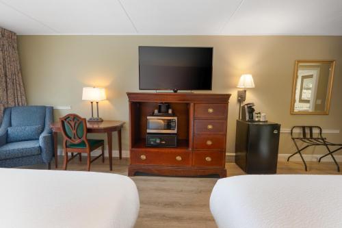 a hotel room with a tv on a dresser at Fireside Inn & Suites Gilford in Gilford