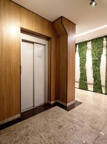 a hallway with a door and plants on the wall at Contagem Centro Hotel in Contagem