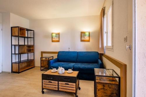 un salon avec un canapé bleu et une table dans l'établissement Résidence Saint-Raphaël Valescure - maeva Home - Studio 4 Personnes Sélection MAE-5437, à Valescure