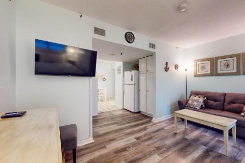 a living room with a couch and a tv on a wall at Plantation Dunes #5404 in Gulf Highlands