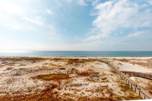 a sandy beach with a fence and the ocean at Plantation Dunes #5404 in Gulf Highlands