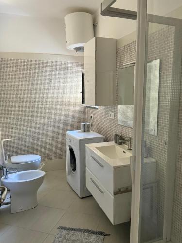 a bathroom with a toilet a sink and a washing machine at Mare Apartment 4 in Scalea