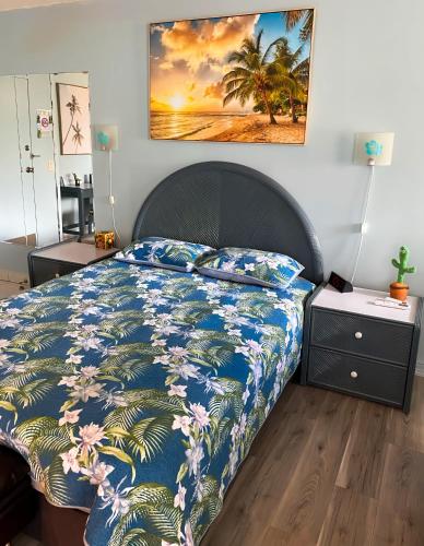 a bedroom with a bed with a blue comforter and palm trees at Renovated Studio Free Parking in Prime Waikiki in Honolulu