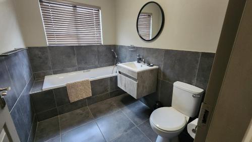a bathroom with a toilet and a sink and a tub at Lloyds - unit 10 in Ermelo