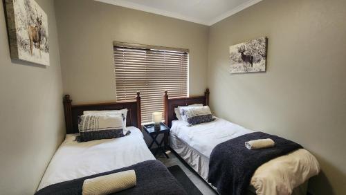 two twin beds in a room with a window at Lloyds - unit 10 in Ermelo