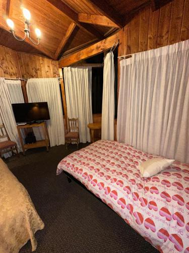 a bedroom with a bed with white curtains and a tv at Hotel los maitenes in Pucón