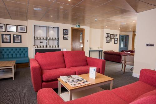 a living room with red couches and a table at Rewley House University of Oxford in Oxford