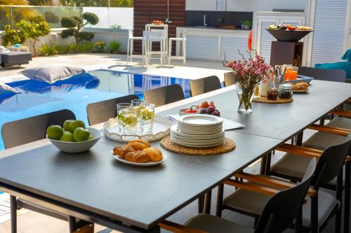 a table with plates of food on it next to a pool at Fig Tree Bay Residences 7 in Protaras