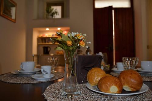 ein Tisch mit Tellern mit Brot und einer Vase mit Blumen in der Unterkunft La luna nel Cortile in Serradifalco