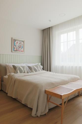 a white bedroom with a large bed and a table at Vila 44 in Druskininkai