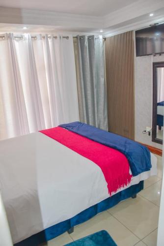 a bedroom with a bed with a red and blue blanket at Modern and Executive 2 Bedroom Townhouse in Bloemfontein