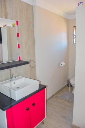 a bathroom with a white sink and a red cabinet at Modern and Executive 2 Bedroom Townhouse in Bloemfontein