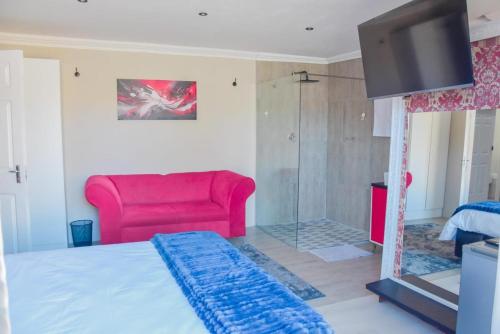 a living room with a red couch and a television at Modern and Executive 2 Bedroom Townhouse in Bloemfontein