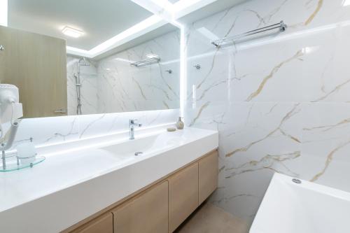 a white bathroom with a sink and a mirror at Bliss Villas Complex with private pool in Hersonissos
