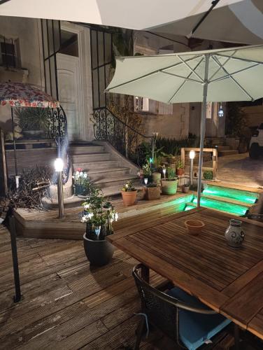 une table en bois avec un parasol et des plantes en pot dans l'établissement Appartement meublé avec parking tv box netflix, à Soyaux