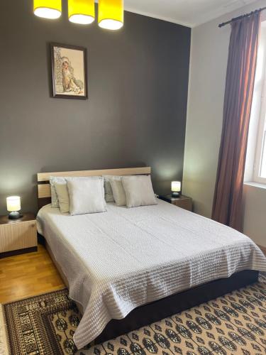 Un dormitorio con una cama grande con sábanas y almohadas blancas. en Dara House, en Plovdiv
