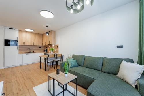 Una sala de estar con un sofá verde y una cocina. en Kriva Apartment 3 City Center Kosice, en Košice