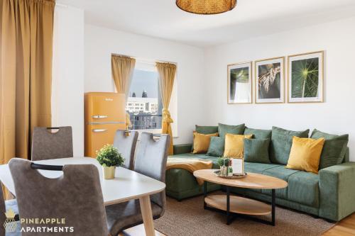 ein Wohnzimmer mit einer grünen Couch und einem Tisch in der Unterkunft PINEAPPLE APARTMENTS - Zwinger XI - 64qm in Dresden