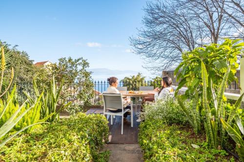 two women sitting at a table in a garden at Villa Monte in Funchal
