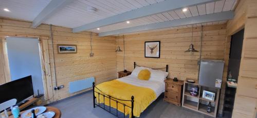 a bedroom with wooden walls and a bed with a yellow blanket at Sea La Vie in Perranporth