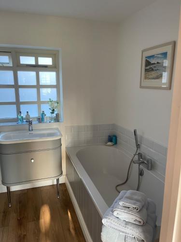 a white bathroom with a tub and a sink at Motts Lodge in Royal Tunbridge Wells