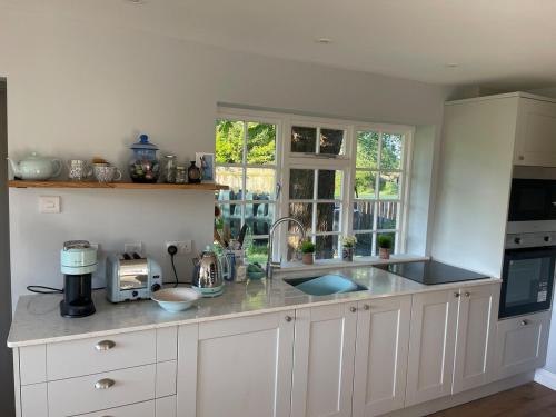 Una cocina con gabinetes blancos y encimera. en Motts Lodge, en Kippings Cross