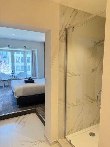 a bathroom with a shower and a bed in a room at Vernieuwde kamers in het centrum van Brugge in Bruges