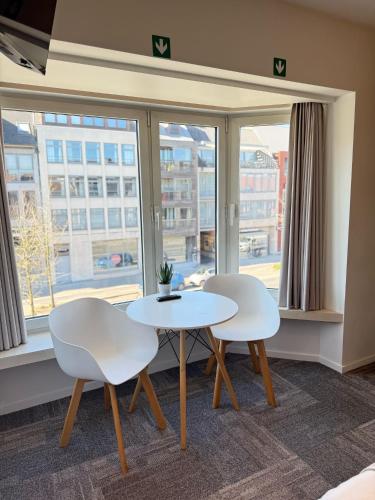 two white chairs and a table in front of a window at Vernieuwde kamers in het centrum van Brugge in Bruges
