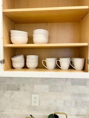 a shelf with white bowls and cups on it at Central 2BR Near Yale WiFi with Washer and Dryer in New Haven