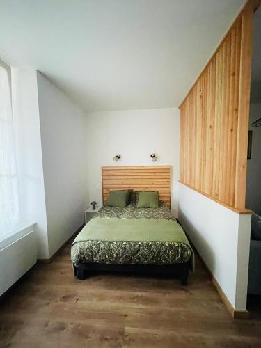 une chambre avec un lit avec une tête de lit en bois dans l'établissement La maison bleue, à Neufchâteau