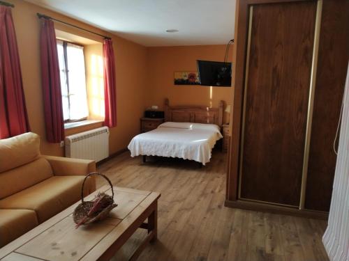 a bedroom with a bed and a couch and a table at Apartamentos Rurales La Caramba in Lamuño