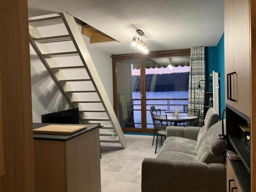 a living room with a couch and a stair case at Le Bord du Lac - Duplex - Meublé 3 étoiles in Malbuisson