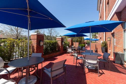 a patio with tables and chairs with blue umbrellas at Holiday Inn Express Leland - Wilmington Area by IHG in Leland