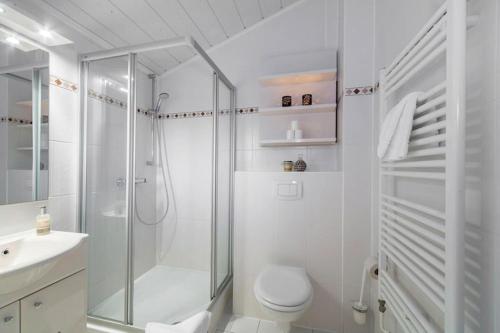 a white bathroom with a shower and a toilet at Doppelhaushälften im Ferien- und Freizeitpark Weissenhäuser Strand in Weissenhäuser Strand