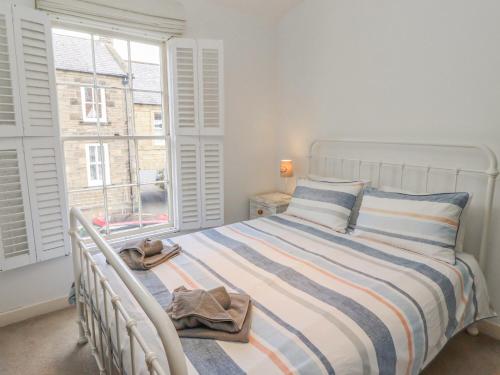 a bedroom with a white bed and a window at Seafield Coach House in Alnwick