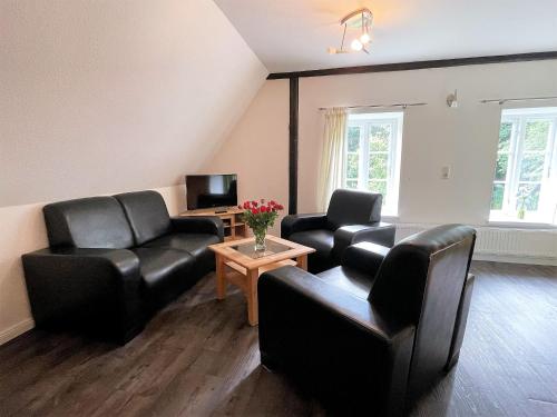 a living room with black leather furniture and a tv at Ferienwohnung Clara Hof Döttgebüll in Aventoft