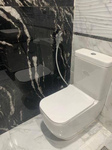 a white toilet in a bathroom with a black wall at H Flat With Roof- One Kattamya in Cairo