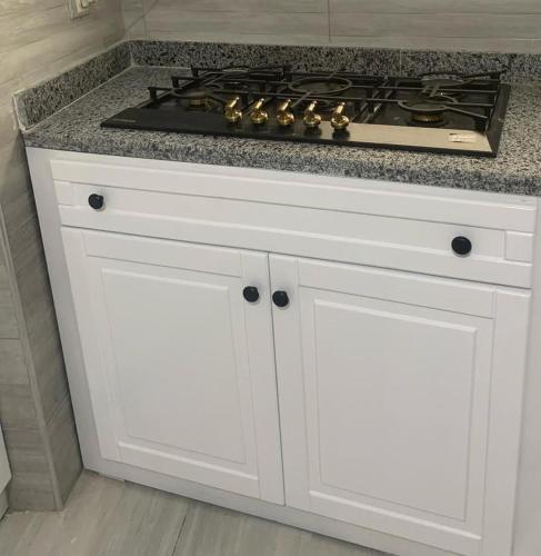 a white kitchen with a stove and white cabinets at H Flat With Roof- One Kattamya in Cairo