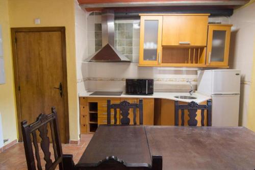 a kitchen with a wooden table and a white refrigerator at Casa Mossèn Batista in Les Iglésies