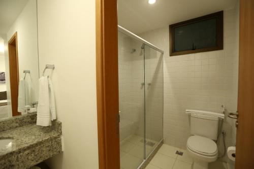 a bathroom with a toilet and a glass shower at Promenade Prime Itaboraí in Itaboraí
