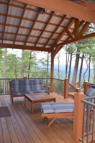 a wooden deck with two benches and a table at Elkhorn Rustic Blowing Rock Cabin Amazing Views in Bailey Camp