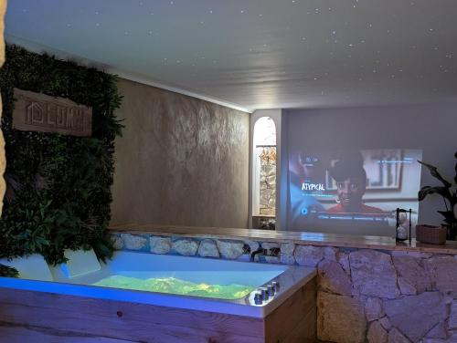 a large tub in a room with a tv at Cottage Lomy avec jacuzzi et sauna privatif in Planguenoual